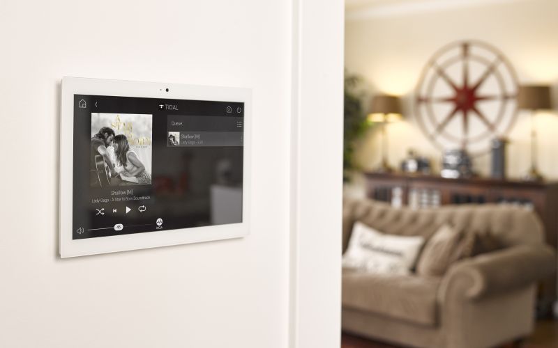 Control4 Touch panel in a able with a traditional home in the background